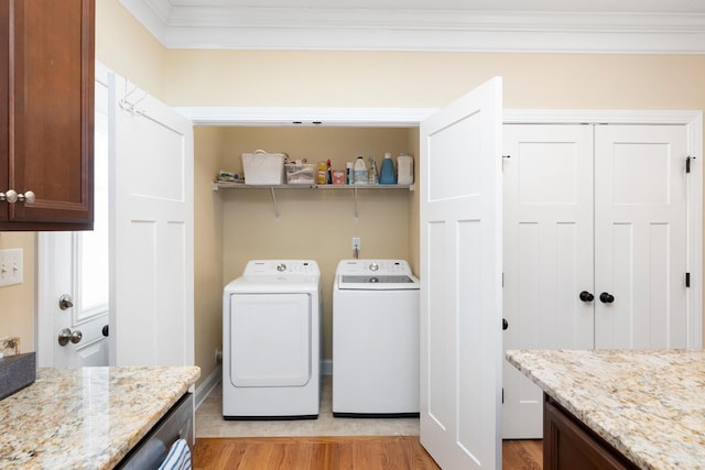 laundry room featuring washing machine and clothes dryer, laundry area, light wood-type flooring, and ornamental molding