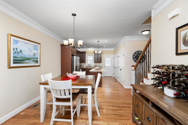 dining space with a notable chandelier, light wood-style floors, baseboards, and ornamental molding