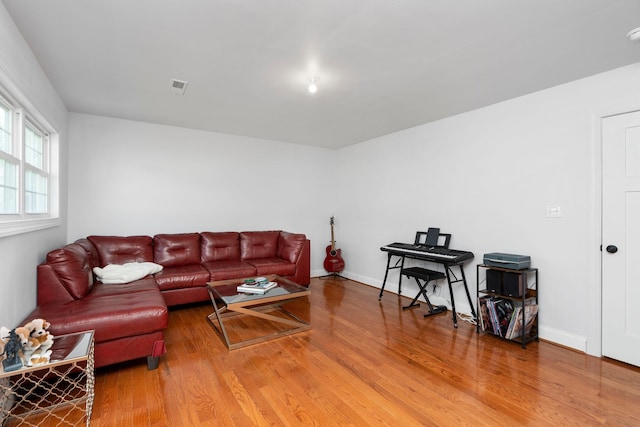 living room featuring visible vents, baseboards, and wood finished floors