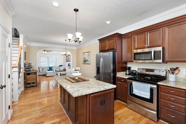 kitchen featuring a center island, open floor plan, ornamental molding, a notable chandelier, and stainless steel appliances