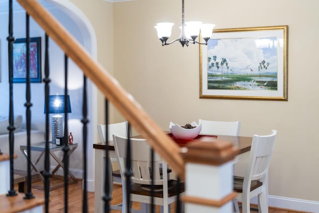 stairway featuring baseboards, an inviting chandelier, and wood finished floors