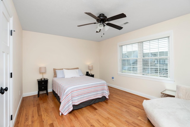 bedroom with light wood-style floors, baseboards, and ceiling fan