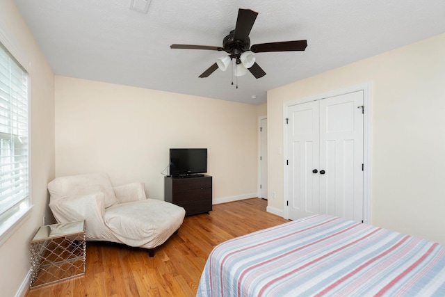 bedroom featuring a closet, ceiling fan, light wood-type flooring, and baseboards