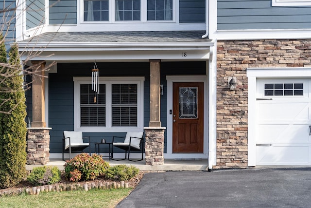 entrance to property featuring stone siding, covered porch, and a shingled roof