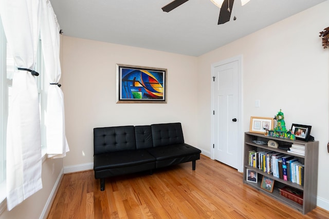 sitting room with a ceiling fan, baseboards, and light wood finished floors