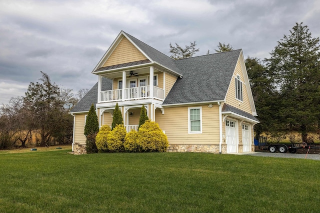 view of front of home with a garage, a balcony, ceiling fan, and a front lawn