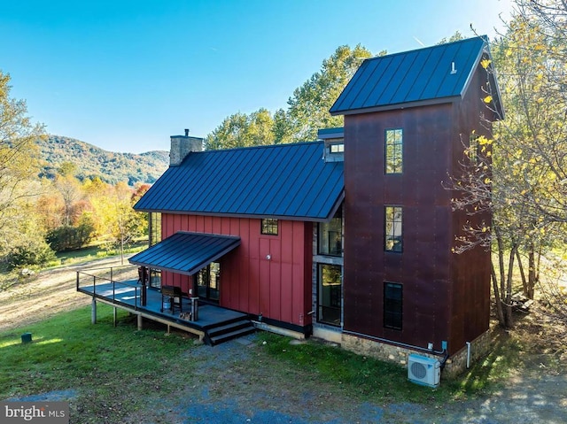 exterior space with a standing seam roof, a yard, board and batten siding, metal roof, and a chimney