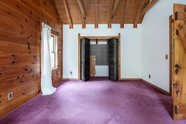 carpeted empty room featuring beamed ceiling, high vaulted ceiling, wood ceiling, and wooden walls