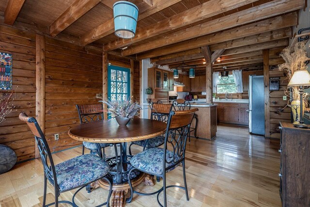 dining space with beam ceiling, plenty of natural light, wooden ceiling, and light wood-type flooring