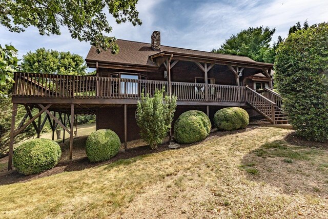 rear view of house featuring a wooden deck and a yard