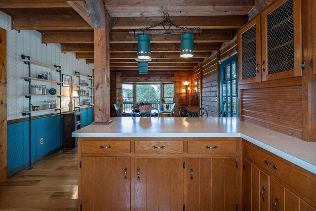 kitchen with hanging light fixtures, light hardwood / wood-style floors, kitchen peninsula, and beamed ceiling