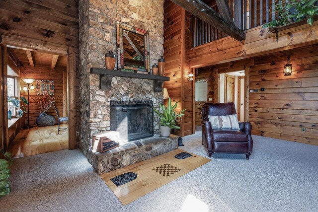 living room with beam ceiling, carpet, a fireplace, and wooden walls