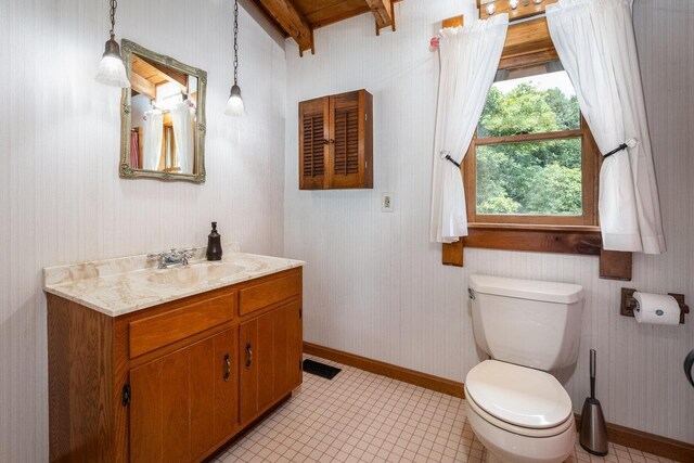 bathroom with vanity, toilet, and beam ceiling