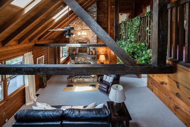 living room featuring lofted ceiling with skylight, carpet flooring, ceiling fan, and wooden walls