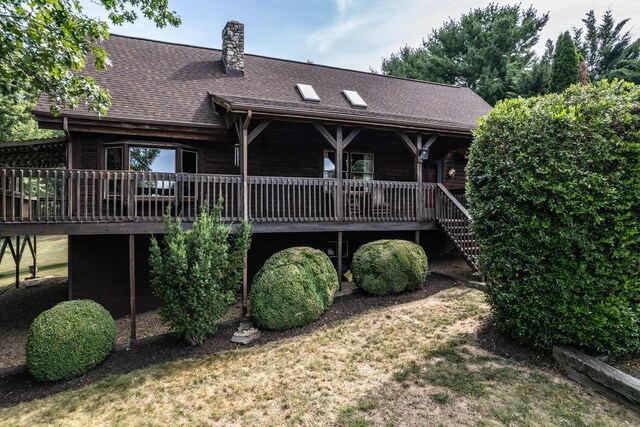 back of property featuring a wooden deck and a lawn