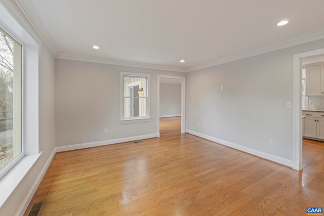 spare room with crown molding, light wood-style flooring, and a healthy amount of sunlight