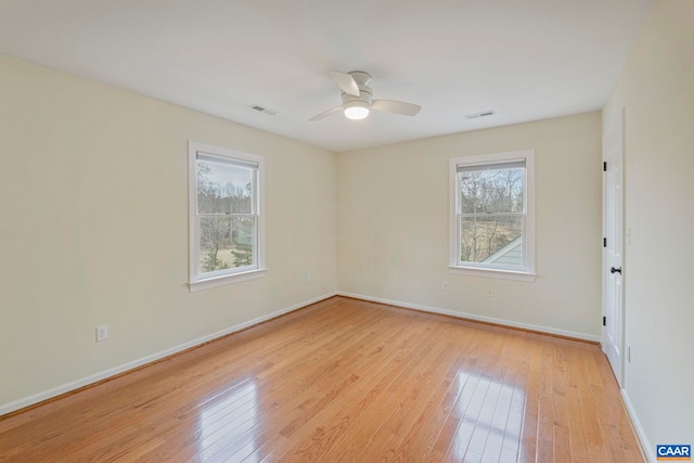 unfurnished room with baseboards, a wealth of natural light, visible vents, and light wood-style floors