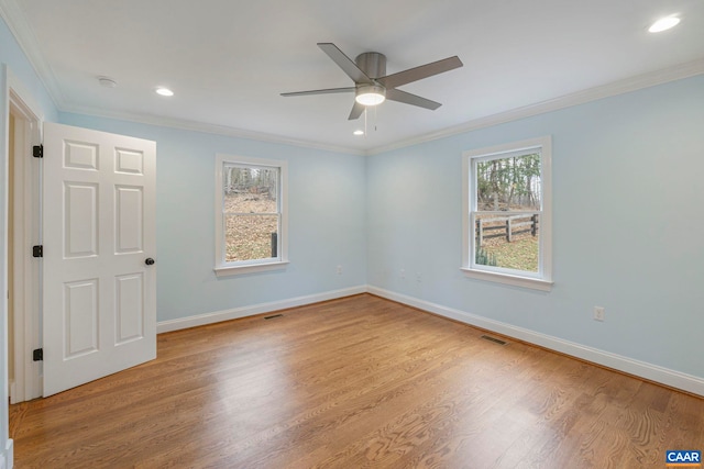 spare room with a wealth of natural light, visible vents, wood finished floors, and ornamental molding