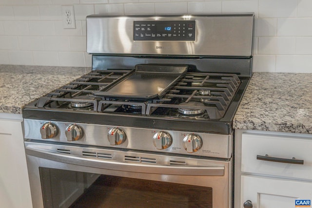 interior details with white cabinetry, backsplash, and stainless steel range with gas stovetop