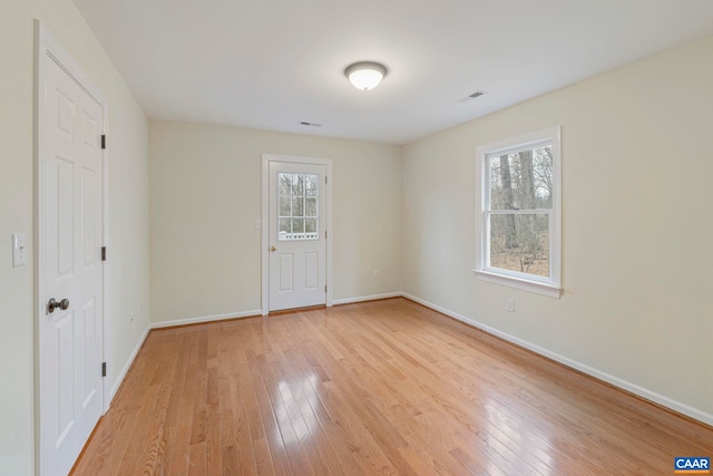 empty room featuring visible vents, light wood-style flooring, and baseboards