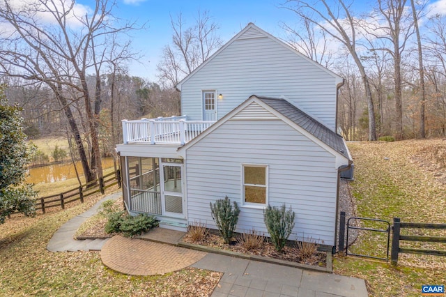 back of house featuring a sunroom, roof with shingles, fence, and a gate