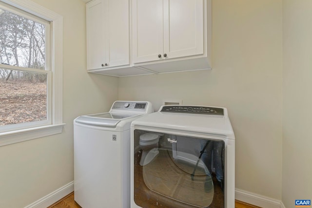 clothes washing area with cabinet space, baseboards, separate washer and dryer, and a wealth of natural light