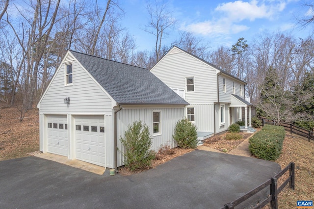 view of home's exterior featuring a shingled roof, fence, and an attached garage