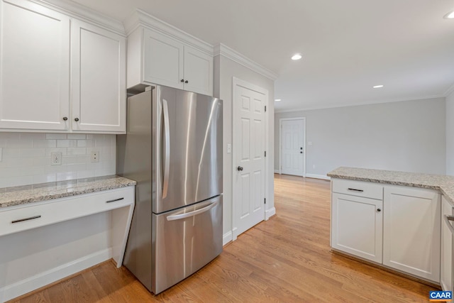 kitchen featuring white cabinets, freestanding refrigerator, crown molding, light wood-style floors, and backsplash