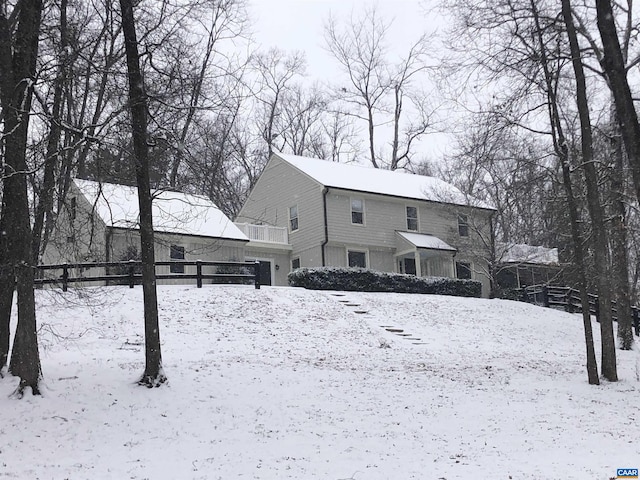 snow covered rear of property featuring fence