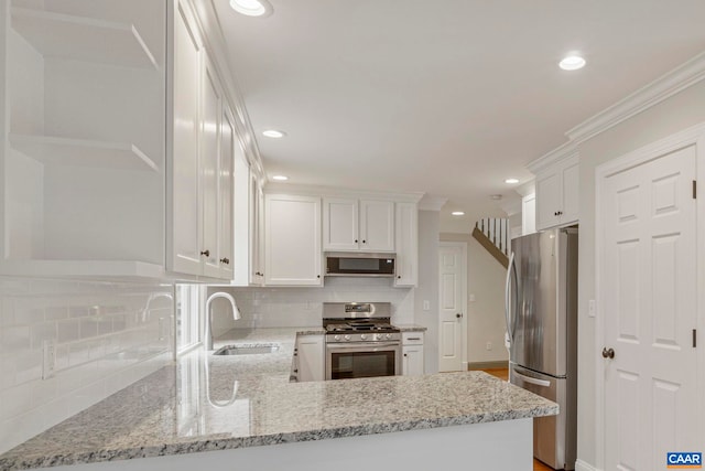 kitchen featuring tasteful backsplash, appliances with stainless steel finishes, ornamental molding, white cabinetry, and a sink