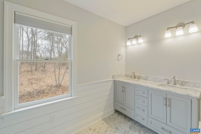 full bath featuring a wealth of natural light, wainscoting, and a sink