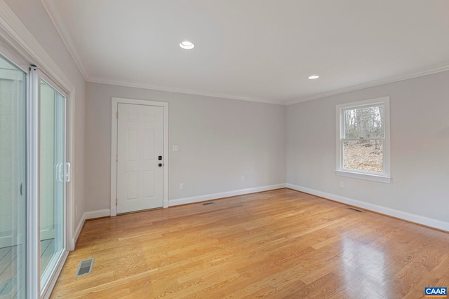 spare room featuring ornamental molding, light wood finished floors, visible vents, and baseboards