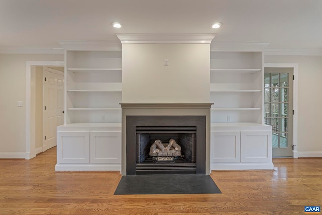 unfurnished living room with baseboards, ornamental molding, a fireplace with flush hearth, and light wood-style floors