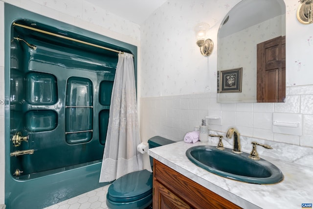 bathroom featuring shower / bathtub combination with curtain, tile walls, wainscoting, wallpapered walls, and vanity