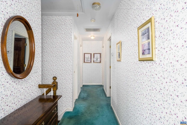 corridor with attic access, dark carpet, wallpapered walls, and visible vents