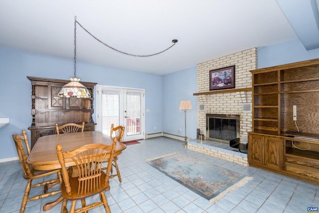 tiled dining area featuring a baseboard heating unit, a brick fireplace, and baseboards