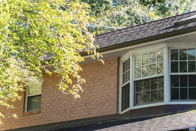 view of side of property featuring brick siding and roof with shingles