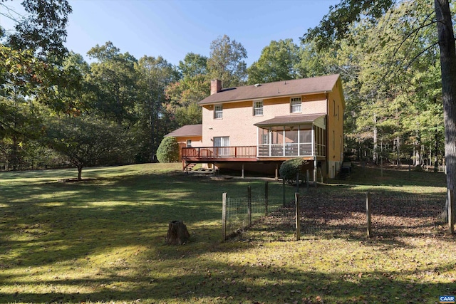 rear view of house featuring a deck, a lawn, a sunroom, and a chimney