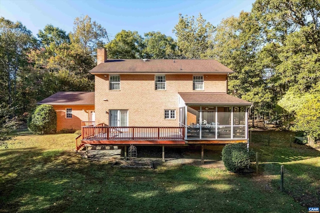 back of house featuring brick siding, a sunroom, a chimney, a deck, and a yard