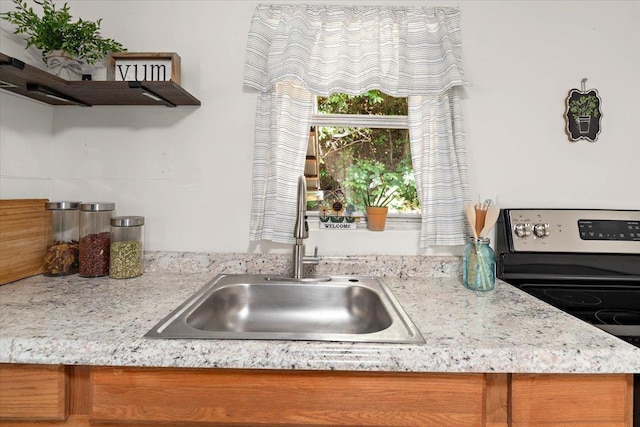 kitchen featuring light stone countertops, sink, and stainless steel range with electric cooktop