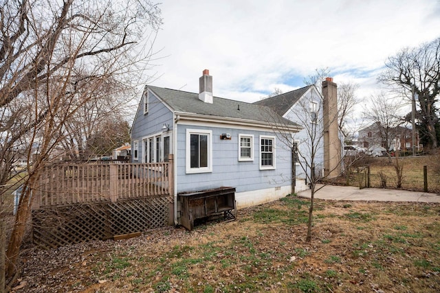 rear view of house featuring roof with shingles, a chimney, and a wooden deck