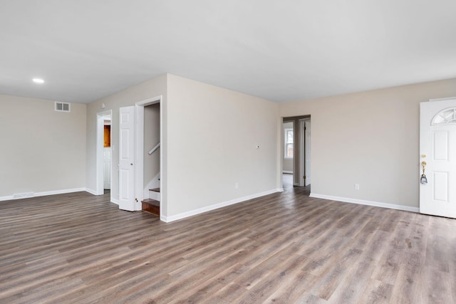 unfurnished living room featuring stairs, wood finished floors, visible vents, and baseboards