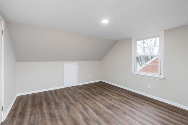 additional living space featuring dark wood-style floors, vaulted ceiling, and baseboards