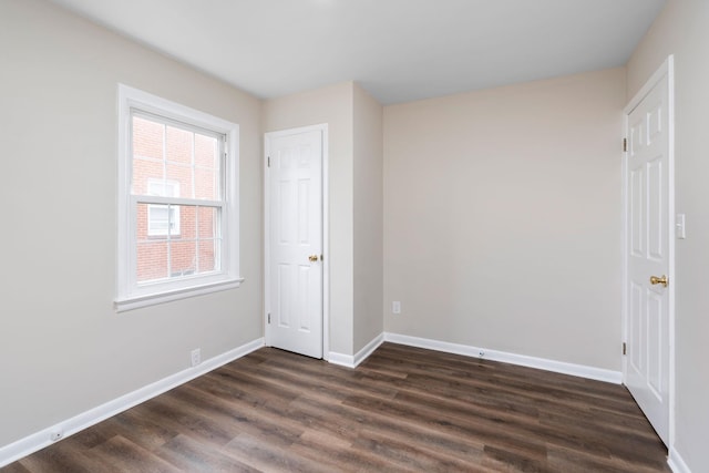 unfurnished bedroom with baseboards and dark wood-type flooring