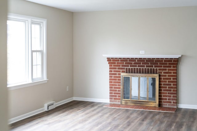 unfurnished living room with a brick fireplace, baseboards, a wealth of natural light, and wood finished floors