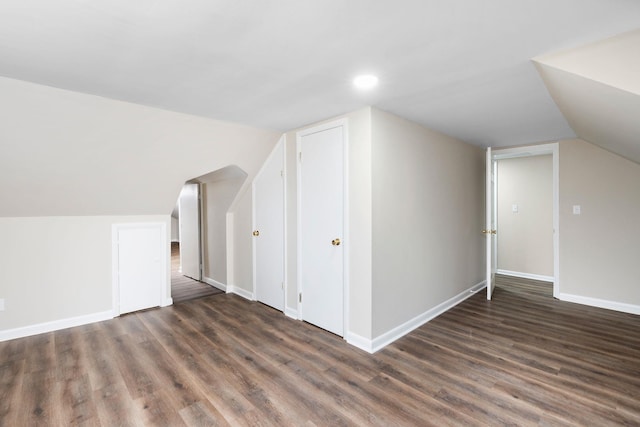 additional living space with dark wood-style floors, baseboards, and vaulted ceiling