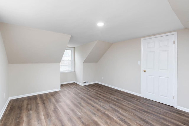 bonus room with lofted ceiling, dark wood-type flooring, visible vents, and baseboards