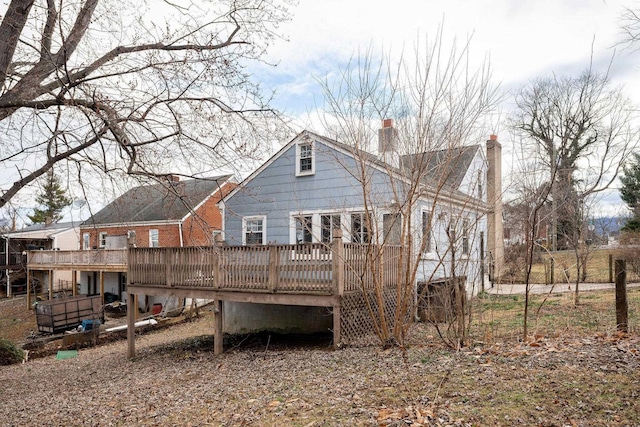 back of house with a chimney and a wooden deck