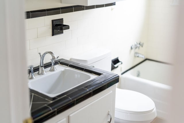 bathroom featuring shower / washtub combination, tile walls, decorative backsplash, toilet, and vanity