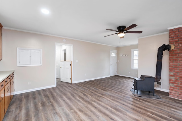 unfurnished living room with visible vents, ornamental molding, wood finished floors, and a wood stove